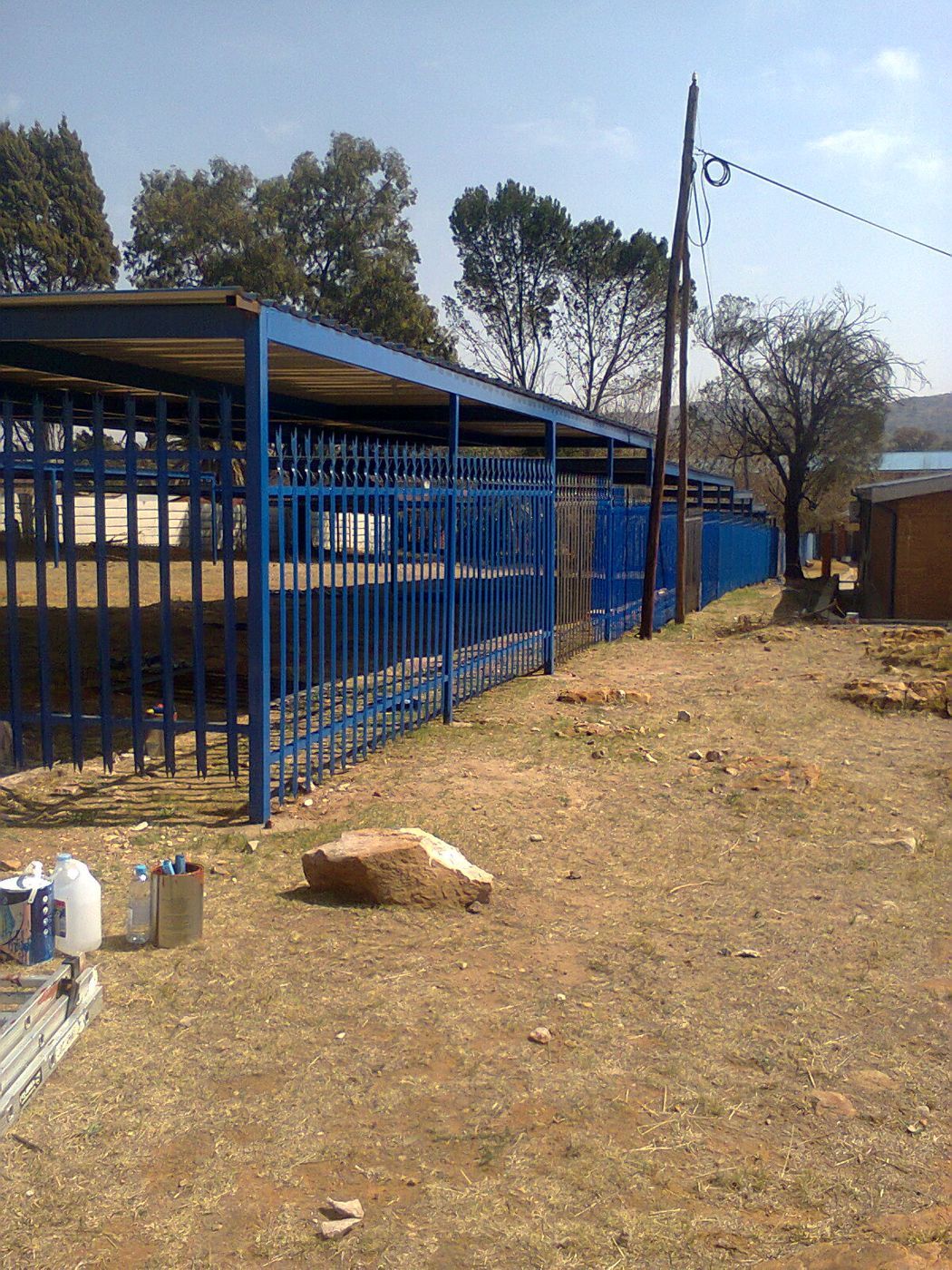 Carports enclosed by matching blue palisade fencing