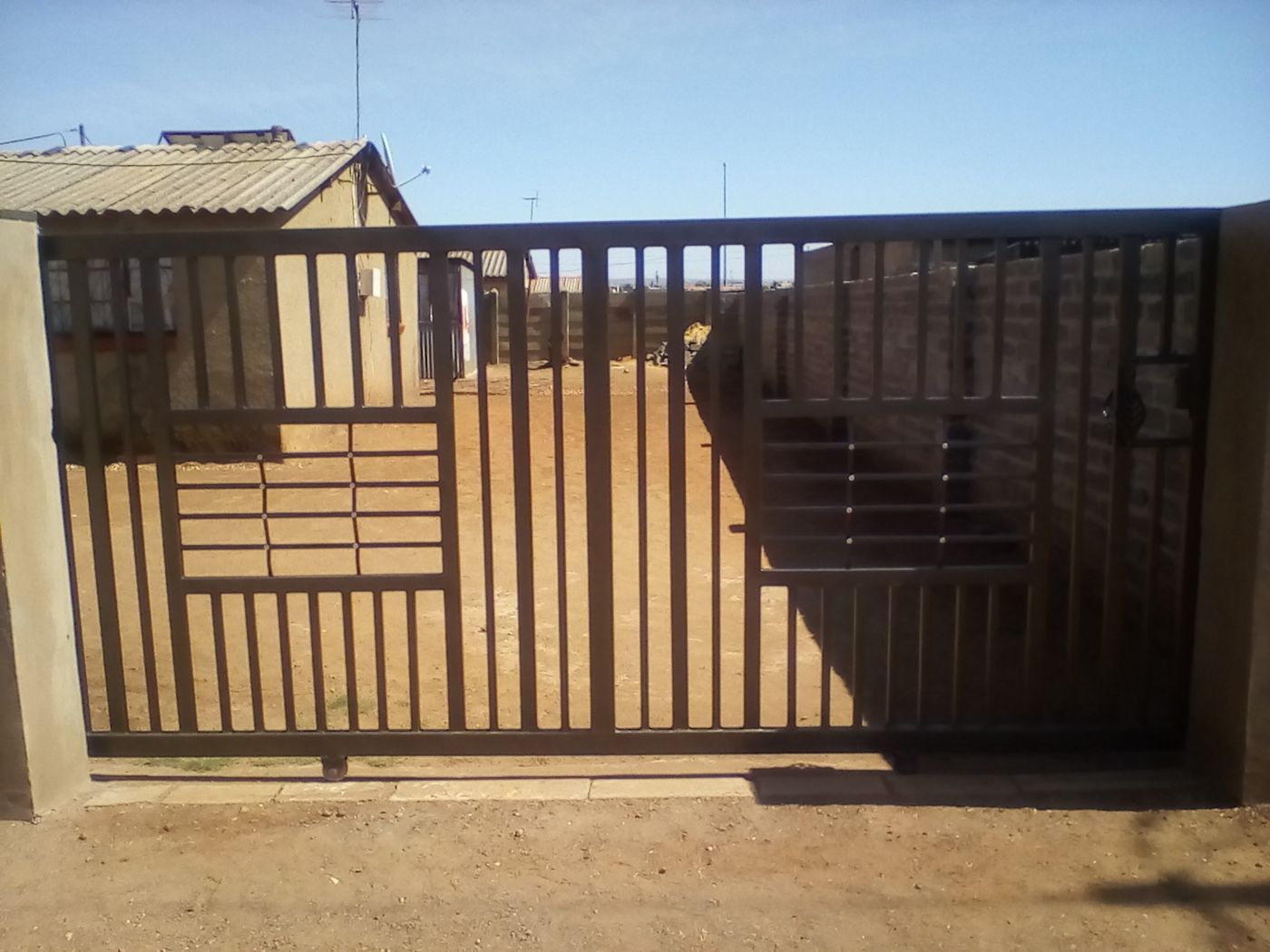 A wide steel driveway gate with a pedestrian door built into it
